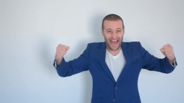 Mavi iş ceketli genç işadamı beyaz arka plandaki kameraya bakıyor.