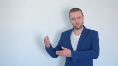 Mavi iş ceketli genç işadamı beyaz arka plandaki kameraya bakıyor.