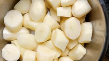 Gri bir tavada soyulmuş patates.