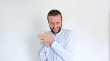 Mavi gözlü yakışıklı bir genç adam ellerini ovuşturuyor.