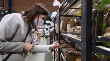 ISRAEL - Netanya, 14 Mart 2020: koruyucu maske takan bir alıcı. Salgın sırasında alışveriş yapmak. Liste almak için acil durum. Koronavirüs salgını sırasında panik alışverişi. Pandemik Karantina Hazırlığı