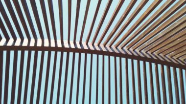 Güneşli bir günde, temiz bir arka planda, tahta bir gölgelik. Uzayda geometri, kesişen çizgiler. Sarının gölgeleri