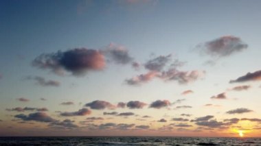Deniz suyunun üzerinde gün batımı manzarası. Alacakaranlıkta gökyüzünde altın güneş ve sahile vuran deniz dalgaları..