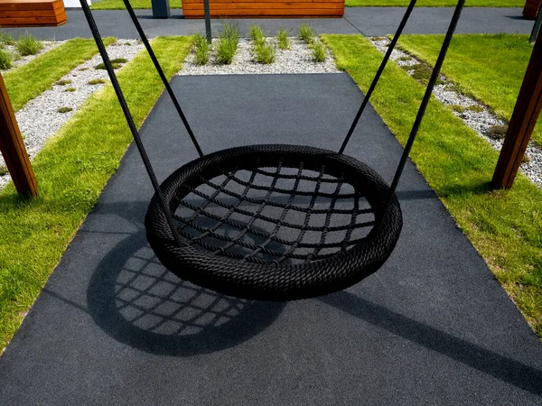 Moderne neue Kinderschaukel aus nächster Nähe, isoliert, auf dem Spielplatz der Wohnanlage. — Stockfoto