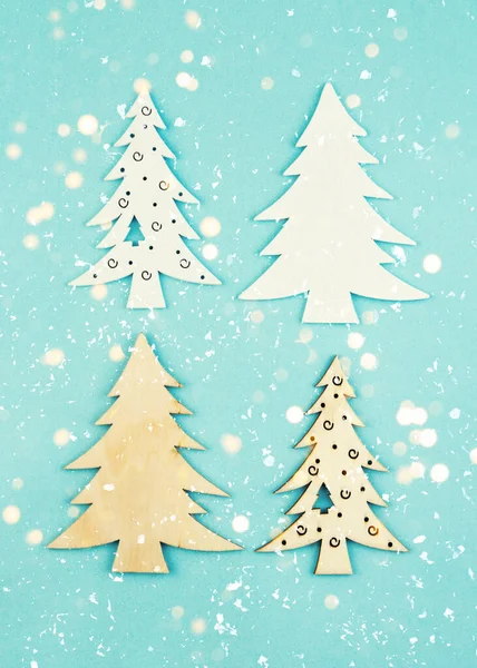 Wooden decorative Christmas trees on a blue background with sparkles. Hanging Christmas decorations. — ストック写真