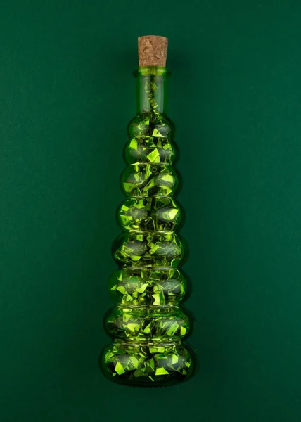 Decorative bottle in the form of a Christmas tree on a green background. — Stock Photo, Image