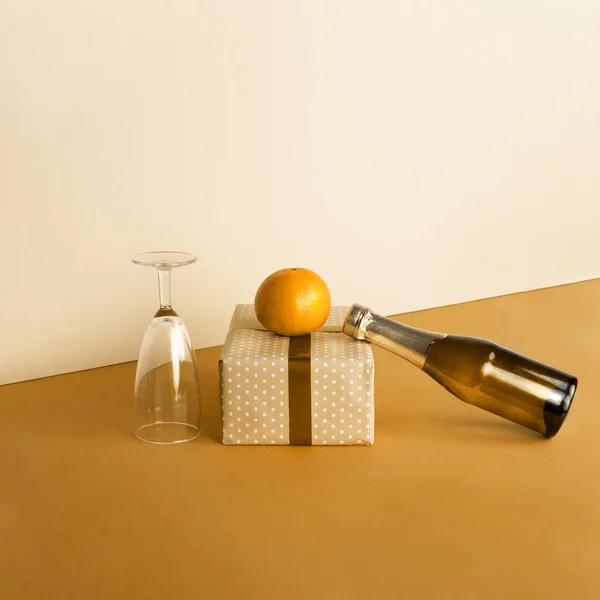 Composición navideña con una botella de champán y mandarina en un estilo minimalista sobre un fondo de color mostaza . — Foto de Stock