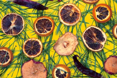 Çam iğneleri ve kuru portakallarla sarı arkaplan.