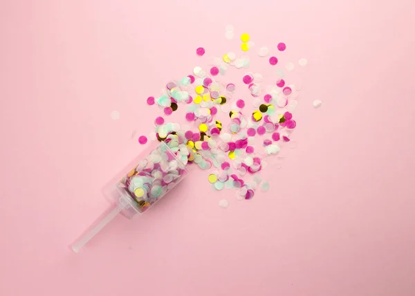 Popper con confetti di carta multicolore su sfondo rosa . — Foto Stock