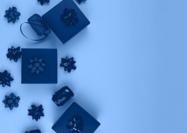 Parlak bir arka planda, desenli bir fiyonkla süslenmiş mavi bir hediye kutusu. Genellikle doğum günü, yıldönümü hediyeleri, hediye kartları, kartpostallar için kullanılır..