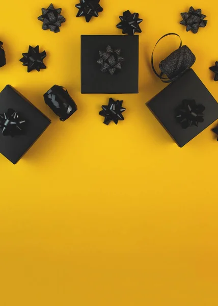Černá dárková krabice na žlutém pozadí, zdobená texturovanou mašlí. Typicky používané k narozeninám, dárky k výročí, dárkové poukazy, pohlednice. — Stock fotografie