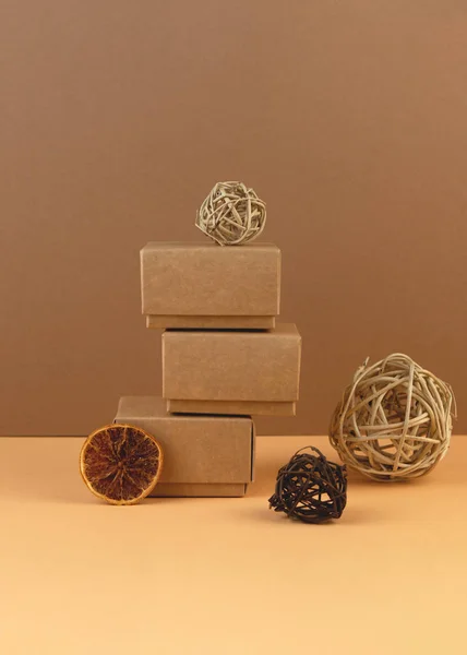 Navidad Cajas de regalo artesanales, bolas de vid y rebanada de naranja seca sobre fondo de color arena pastel . —  Fotos de Stock