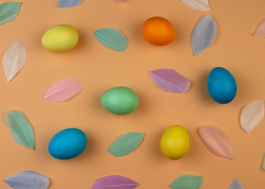 Renkli paskalya yumurtaları ve pastel arka plandaki tüylerin Paskalya kompozisyonu. Mutlu Paskalyalar.