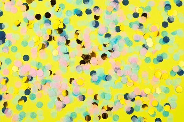 Coriandoli multicolori festivi sparsi su sfondo giallo. Concetto vacanza. Texture a pois pastello . — Foto Stock