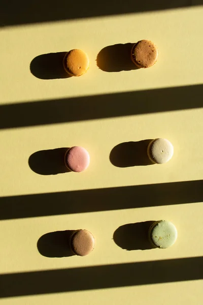 Macaron piatto moderno di composizione laica pastello su sfondo giallo chiaro con ombra scura . — Foto Stock