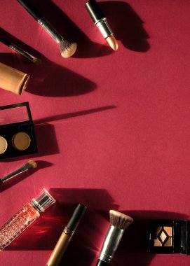 Kadın düz makyaj arka planında koyu gölgeli dekoratif kozmetik setiyle yatıyordu. Krem, ruj, parfüm, rimel ve fırça..