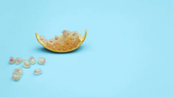 Eine Scheibe gelbe Granatapfelfrucht und weiße Körner auf blauem Hintergrund — Stockfoto