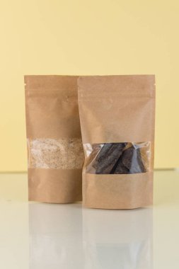 Kahverengi kraft kağıdından çanta, sarı arka planda market önü manzaralı. Gıda ve mallar için ambalaj tasarımı. Ağırlık ürünleri için pencereli paketler.
