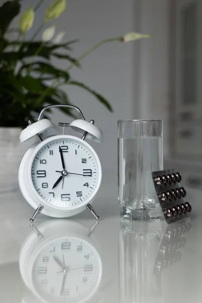 Vit Väckarklocka Och Medicinska Piller Med Ett Glas Vatten Bordet — Stockfoto