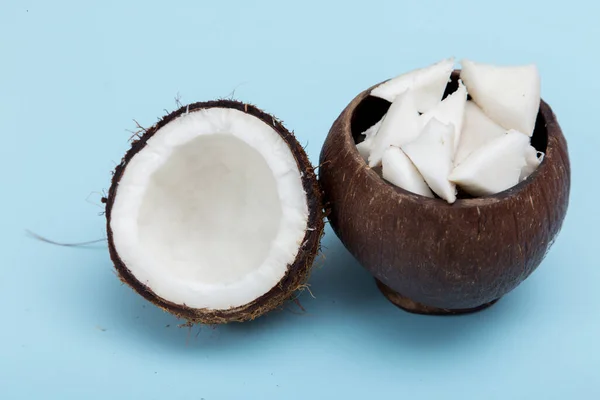 Hälften Kokosnöt Och Kokosnöt Bitar Trä Vas Blå Bakgrund Framifrån — Stockfoto