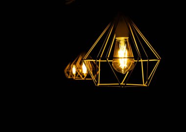 Siyah arka planda izole edilmiş sarı lambalı modern metal abajur. Soyut iç parça.