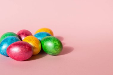 Pembe arka planda renkli paskalya yumurtaları. Mutlu Paskalya kompozisyonu. Boşluğu kopyala.
