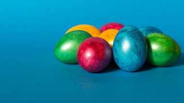 Mavi arka planda renkli paskalya yumurtaları. Mutlu Paskalya kompozisyonu.