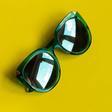 Eski moda yeşil gözlüklü, gölgeli ve sarı arka planda gözlüklü gökyüzünün yansıması. Güzel moda yeşil güneş gözlükleri. Modaya uygun yaz konsepti..