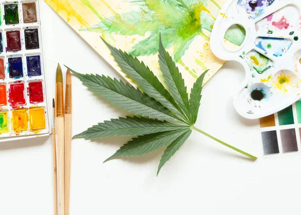Ensemble de peintures aquarelles, pinceaux d'art, palette et album vierge. Feuille de marijuana. Le cannabis révèle la créativité. Le concept d'art . — Photo