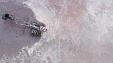 Asian man working on the rice fields with the tractor. Image taken from above with a drone.