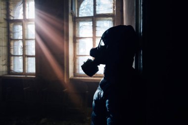 Pencerede gaz maskesi takan bir kadının dramatik portresi yıkılmış bir binadaki umudu sembolize ediyor..