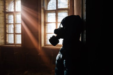 Pencerede gaz maskesi takan bir kadının dramatik portresi yıkılmış bir binadaki umudu sembolize ediyor..