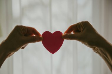 Güneşli bir günde kalp şeklini pencereye dayayan eller.. 