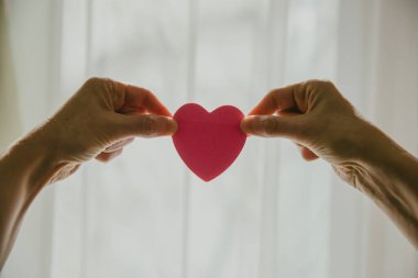 Güneşli bir günde kalp şeklini pencereye dayayan eller.. 