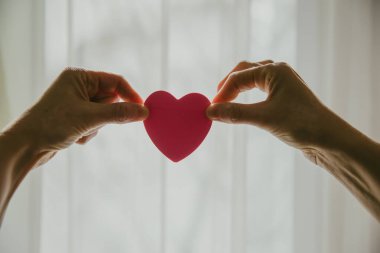 Güneşli bir günde kalp şeklini pencereye dayayan eller.. 