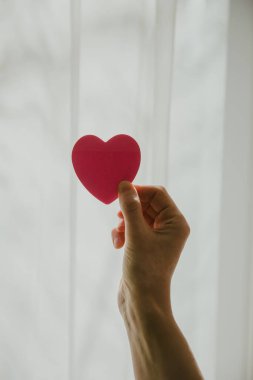 Güneşli bir günde kalp şeklini pencereye dayayan eller.. 