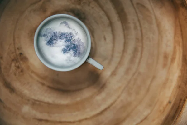 Coffee cup with a mountain on a wooden background. Travel, wanderlust concept.