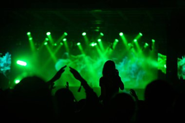 Sahne ışıkları ve bir müzik festivalinde elleri havada seyirci kalabalığı. Taraftarlar parti havasını seviyor.