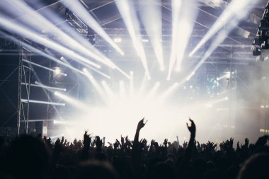 Sahne ışıkları ve bir müzik festivalinde elleri havada seyirci kalabalığı. Taraftarlar parti havasını seviyor.