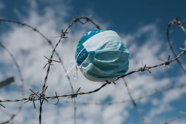 Dünya 'daki cerrahi maske. Salgın hastalık konsepti. Covid-19 / Coronavirus virüsü bulaşmış bir dünya. 