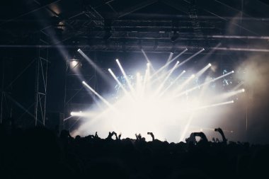 Sahne ışıkları ve bir müzik festivalinde elleri havada seyirci kalabalığı. Taraftarlar parti havasını seviyor.