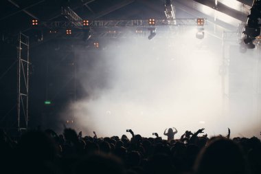Sahne ışıkları ve bir müzik festivalinde elleri havada seyirci kalabalığı. Taraftarlar parti havasını seviyor.