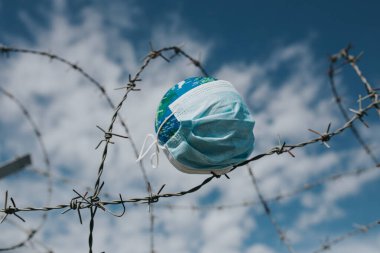 Dünya 'daki cerrahi maske. Salgın hastalık konsepti. Covid-19 / Coronavirus virüsü bulaşmış bir dünya. 