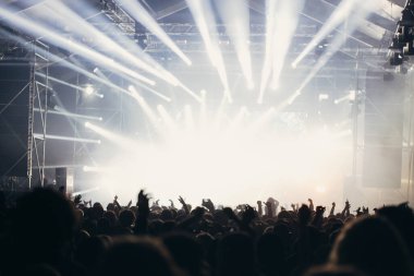 Sahne ışıkları ve bir müzik festivalinde elleri havada seyirci kalabalığı. Taraftarlar parti havasını seviyor.