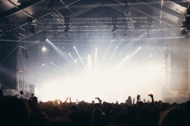 Sahne ışıkları ve bir müzik festivalinde elleri havada seyirci kalabalığı. Taraftarlar parti havasını seviyor.