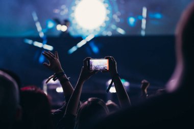 Sahne ışıkları ve bir müzik festivalinde elleri havada seyirci kalabalığı. Taraftarlar parti havasını seviyor.