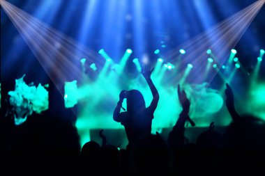 Sahne ışıkları ve bir müzik festivalinde elleri havada seyirci kalabalığı. Taraftarlar parti havasını seviyor.