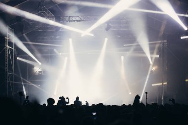 Sahne ışıkları ve bir müzik festivalinde elleri havada seyirci kalabalığı. Taraftarlar parti havasını seviyor.