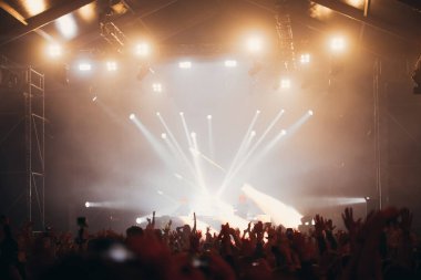 Sahne ışıkları ve bir müzik festivalinde elleri havada seyirci kalabalığı. Taraftarlar parti havasını seviyor.