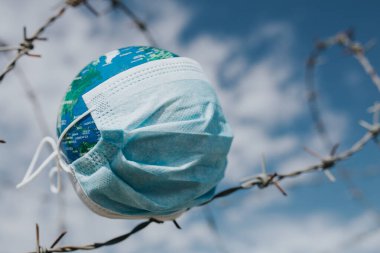 Dünya 'daki cerrahi maske. Salgın hastalık konsepti. Covid-19 / Coronavirus virüsü bulaşmış bir dünya. 